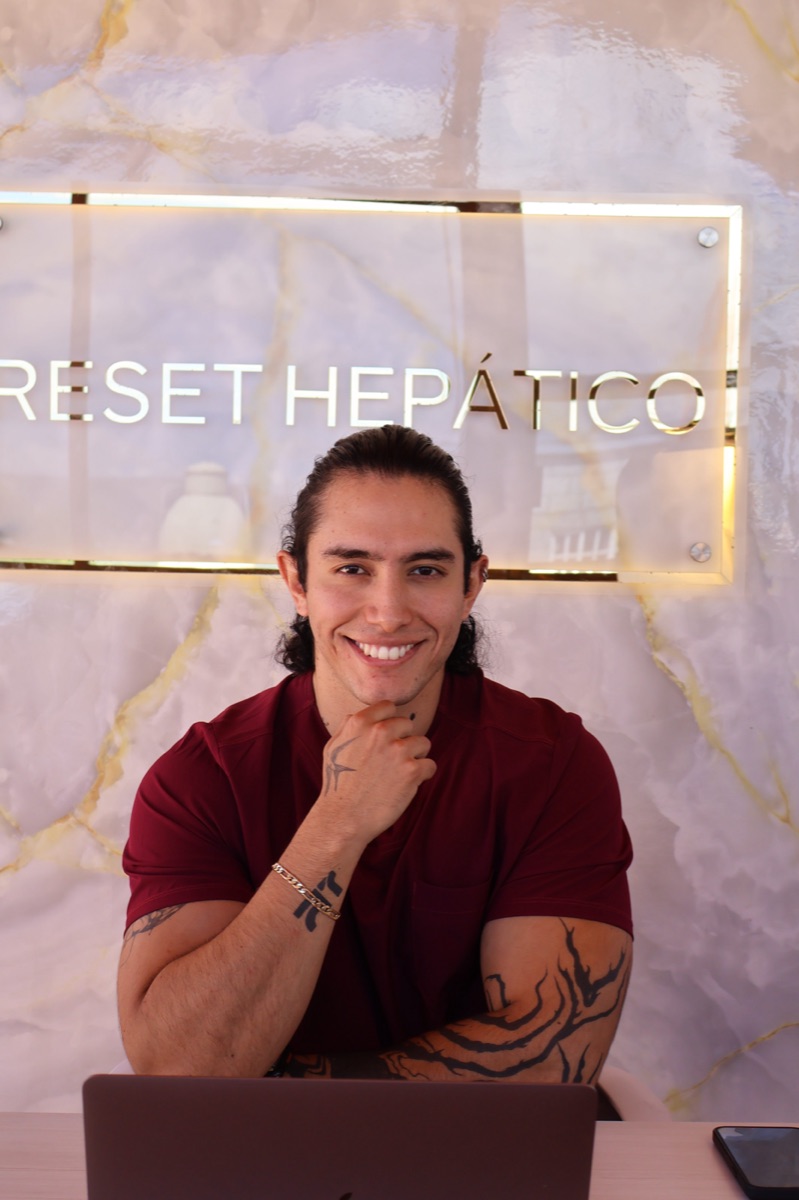 Fundador de Araoz Fitness sonriendo frente al lema Reset Hepático en su estudio